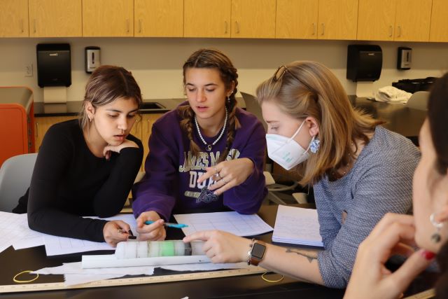 NEIA Science Teacher, Emma Christman, explaining science experiment to 10th graders